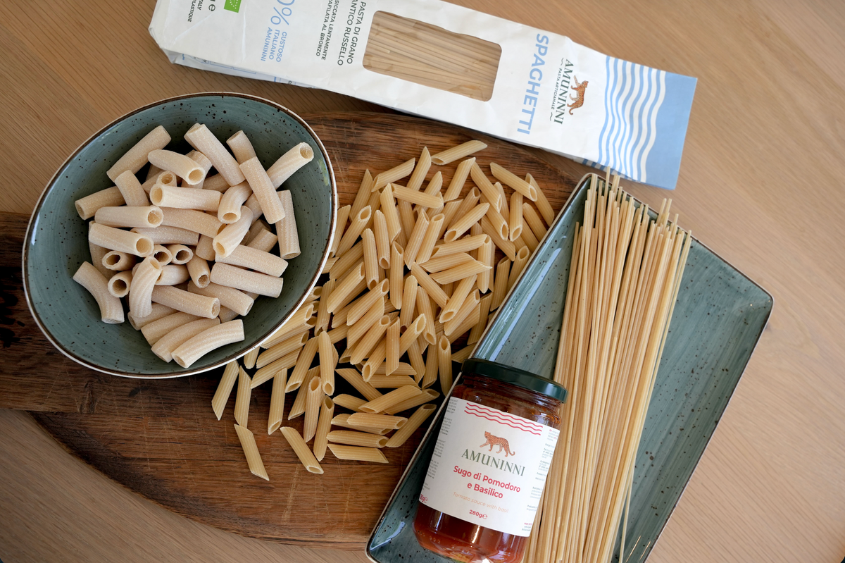 Amuninni ancient grain pasta shapes with a jar of Sicilian tomato and basil sauce.